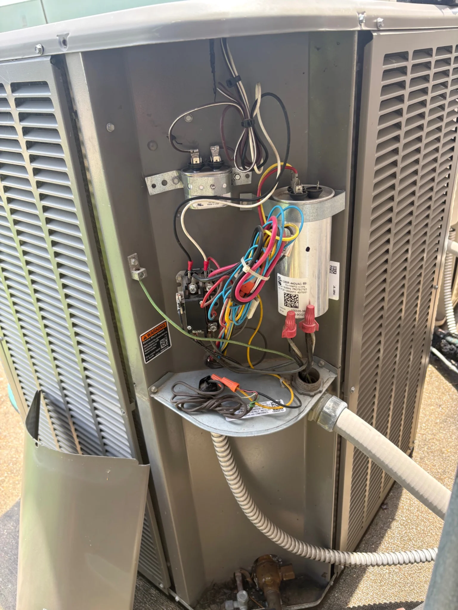 HVAC technician inspecting capacitors, contactors, wiring, and electrical components during an AC inspection