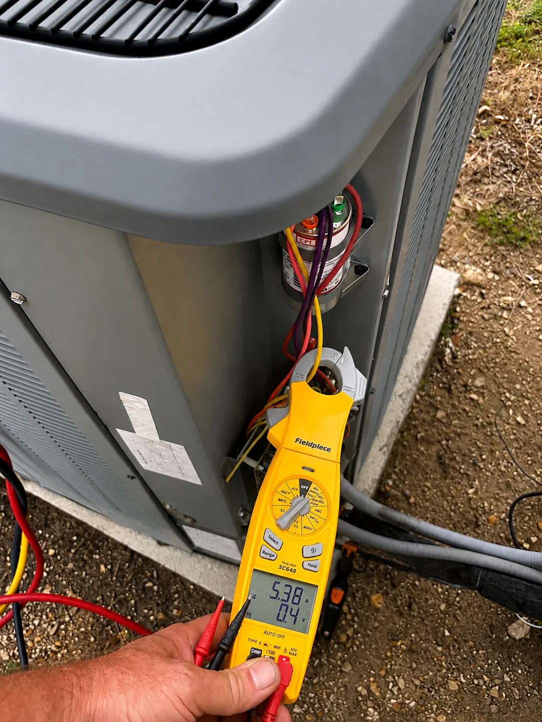 HVAC technician performing AC electrical diagnostics during maintenance service in Caddo Mills TX